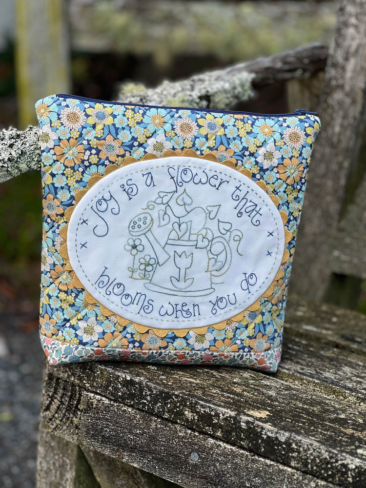 Decorative pouch with floral pattern and embroidered design on a wooden surface