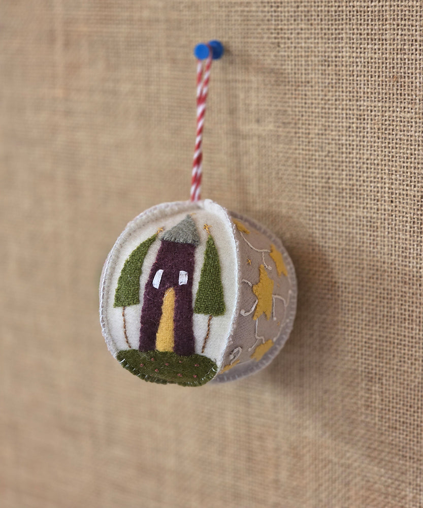 Felt ornament with a house design on a textured brown background
