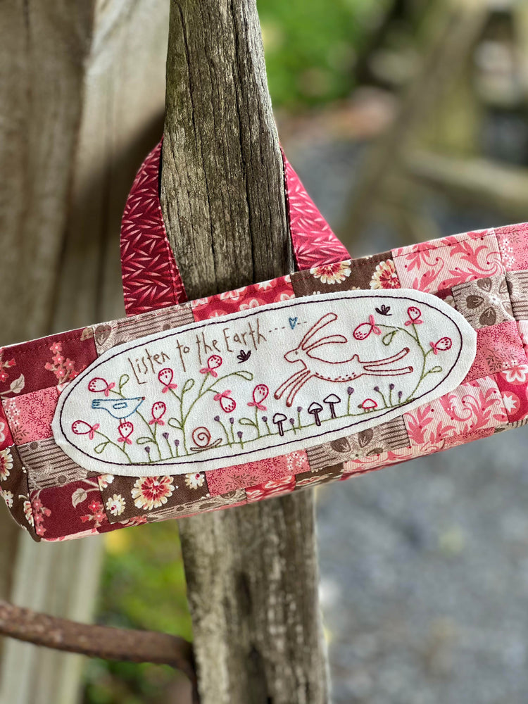 Decorative small bag with floral design and text on a wooden post outdoors